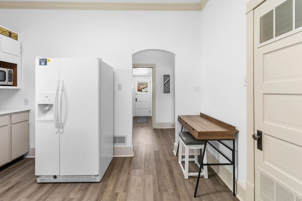 A kitchen with a white refrigerator, wooden cabinets, and a wooden dining table with two chairs.