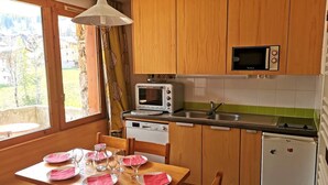 A compact kitchen with wooden cabinets, a microwave, a toaster, and a small refrigerator. - La Clairière 1 - Nice divisible studio with a mountain view (LES AVANCHERS VALMOREL)