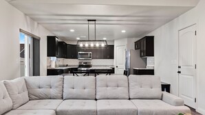 A modern kitchen with dark cabinets, a large island, and a dining area.