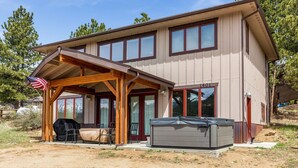 A two-story house with a covered patio, a barbecue grill, and a hot tub. - Show Me Mountain Views -- 20-ncd0130 3 Bedroom Home by RedAwning (Estes Park)