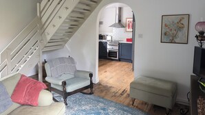 Eine Treppe mit weißer Handläufung führt zu einem Küchenbereich mit Herd und Backofen.