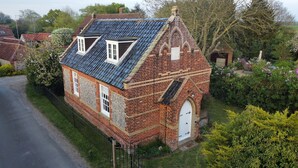 Ein traditionelles Backsteinhaus mit Satteldach, einer kleinen angebauten Garage und einem gepflegten Garten.