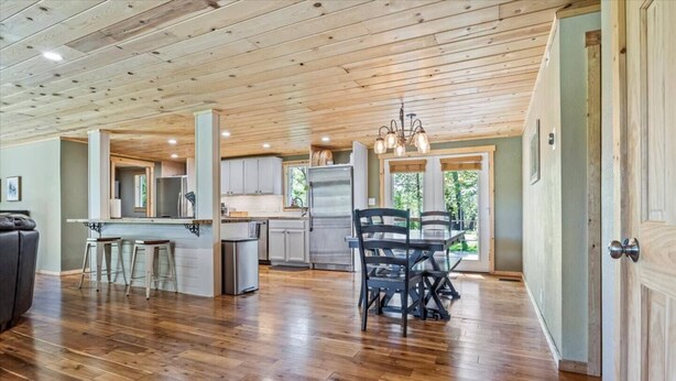 Una cocina amplia con piso de madera, un comedor con mesa y sillas, y vistas a través de amplios ventanales.