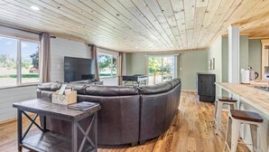 Una sala de estar moderna con un sofá seccional, una mesa de centro de madera y una zona de bar con taburetes.