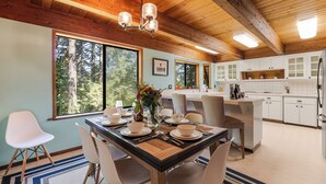 Una cocina moderna con armarios blancos, una isla central y un comedor con una mesa dispuesta para cuatro.