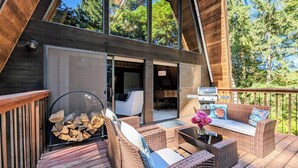 Una terraza de madera con muebles de mimbre, una parrilla y un brasero.