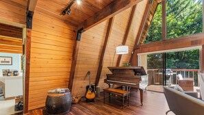 Un interior de madera con un piano, una guitarra y un barril.