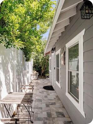 A covered outdoor area with a tiled floor, a wooden bench, and a table. - Tiny cozy house (Alhambra)