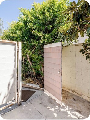 A gated entrance with a concrete pathway leading to a white building. - Tiny cozy house (Alhambra)