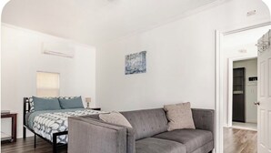 A bedroom with a bed, a grey sofa, and a painting on the wall.