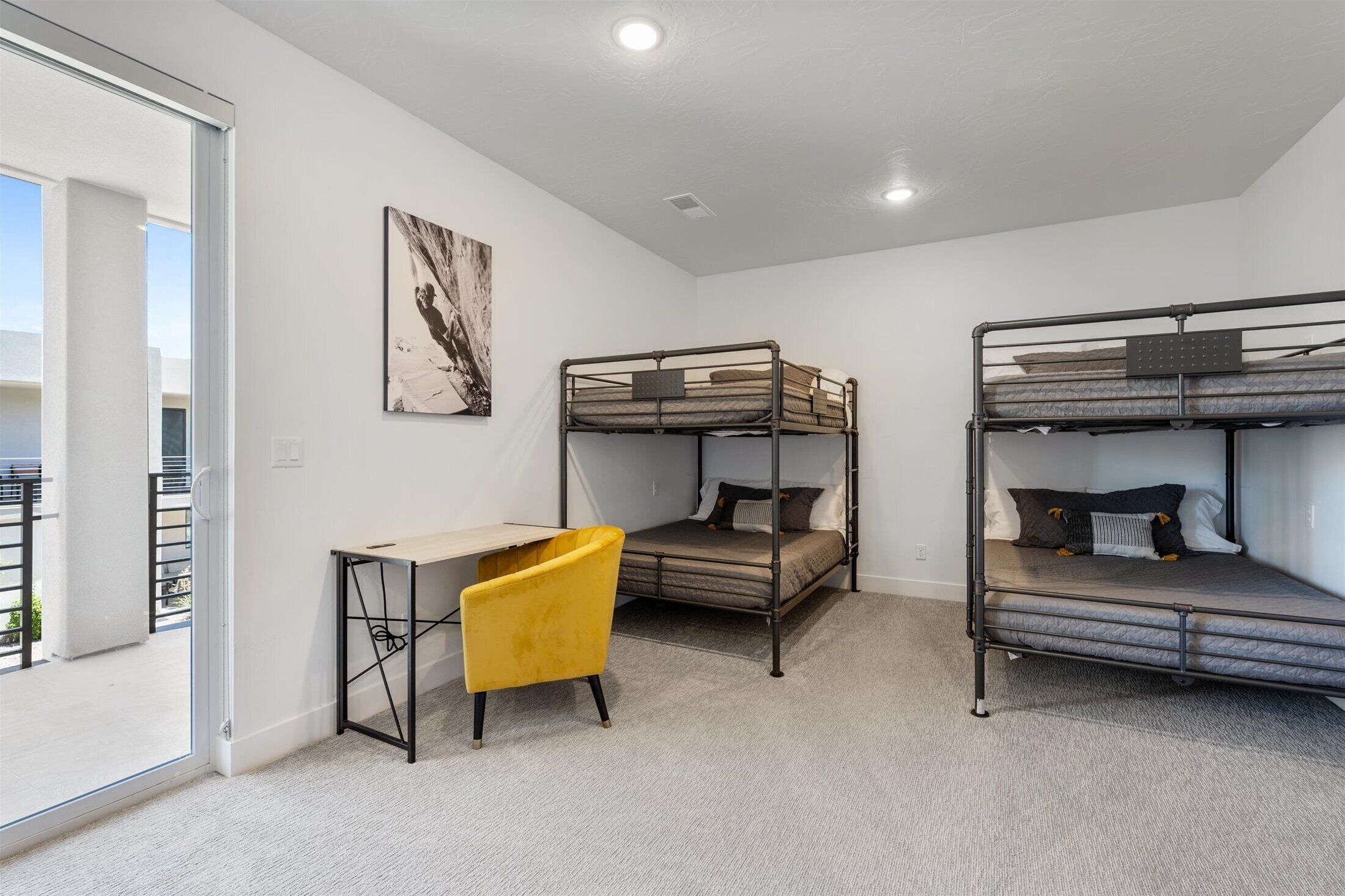 A dormitory room with bunk beds, a desk, and a chair.