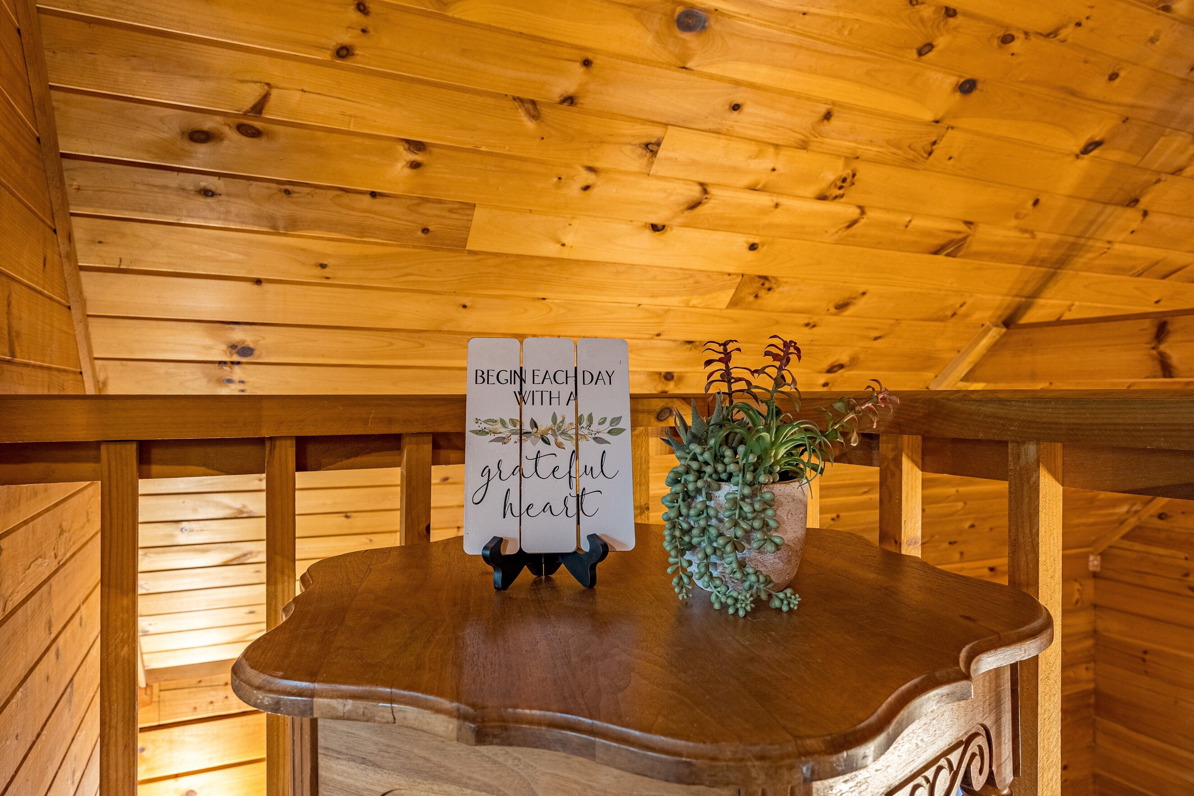 A wooden interior with a bench, a sign with a motivational message, and a potted plant.