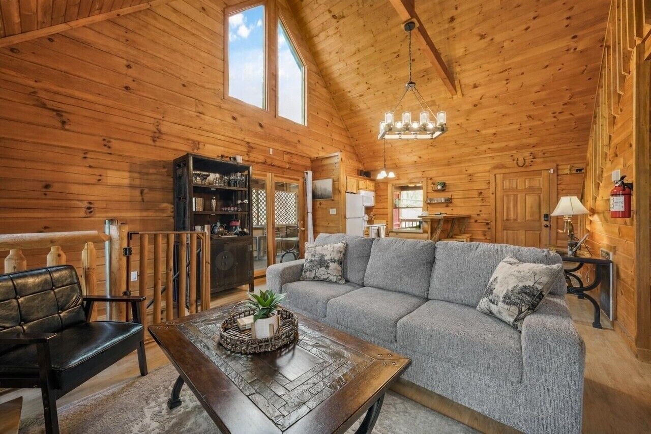 Een knus blokhutinterieur met een houten plafond, een bank, een bijzettafeltje en een open haard.