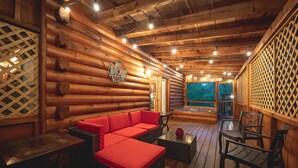 A log cabin interior with a red sofa, wicker chairs, and a wooden table.