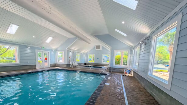 An indoor swimming pool with clear water, a brick floor, and large windows. - **NEW FLOORS** BEACH HOUSE, CENTRAL AIR, GOLF CART INCLUDED (Myrtle Beach)