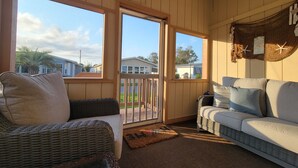 A cozy room with wicker furniture, a white sofa, and a view of the outside. - **NEW FLOORS** BEACH HOUSE, CENTRAL AIR, GOLF CART INCLUDED (Myrtle Beach)