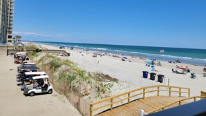 A beach with a wooden boardwalk, beachgoers, and parked golf carts. - **NEW FLOORS** BEACH HOUSE, CENTRAL AIR, GOLF CART INCLUDED (Myrtle Beach)