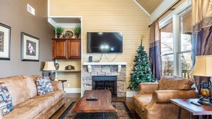 Ein Wohnzimmer mit Kamin aus Stein, Ledersofas, einem Fernseher und einem Weihnachtsbaum.