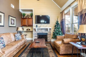 Una sala de estar con chimenea de piedra, sofás de cuero, un televisor y un árbol de Navidad.