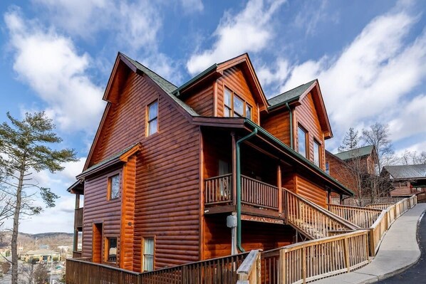 A two-story log cabin with a balcony, a covered porch, and a steep driveway. - Spacious Cabin, Sleeps 6・Pool Table・Hot tub (Pigeon Forge)