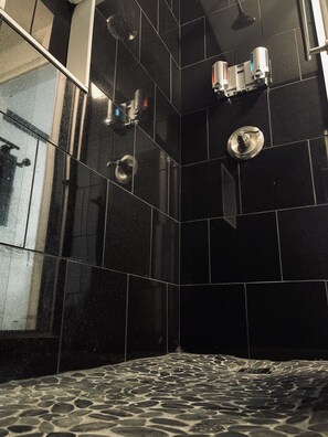 Enjoy a refreshing shower in a spacious bathroom with multiple showerheads.