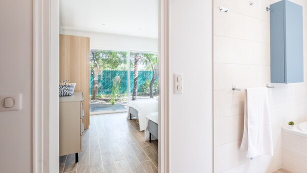 A modern bathroom with a bathtub, a towel hanging on the wall, and a shower area. - 2-Bedroom Apartment with Garden (Cannes)