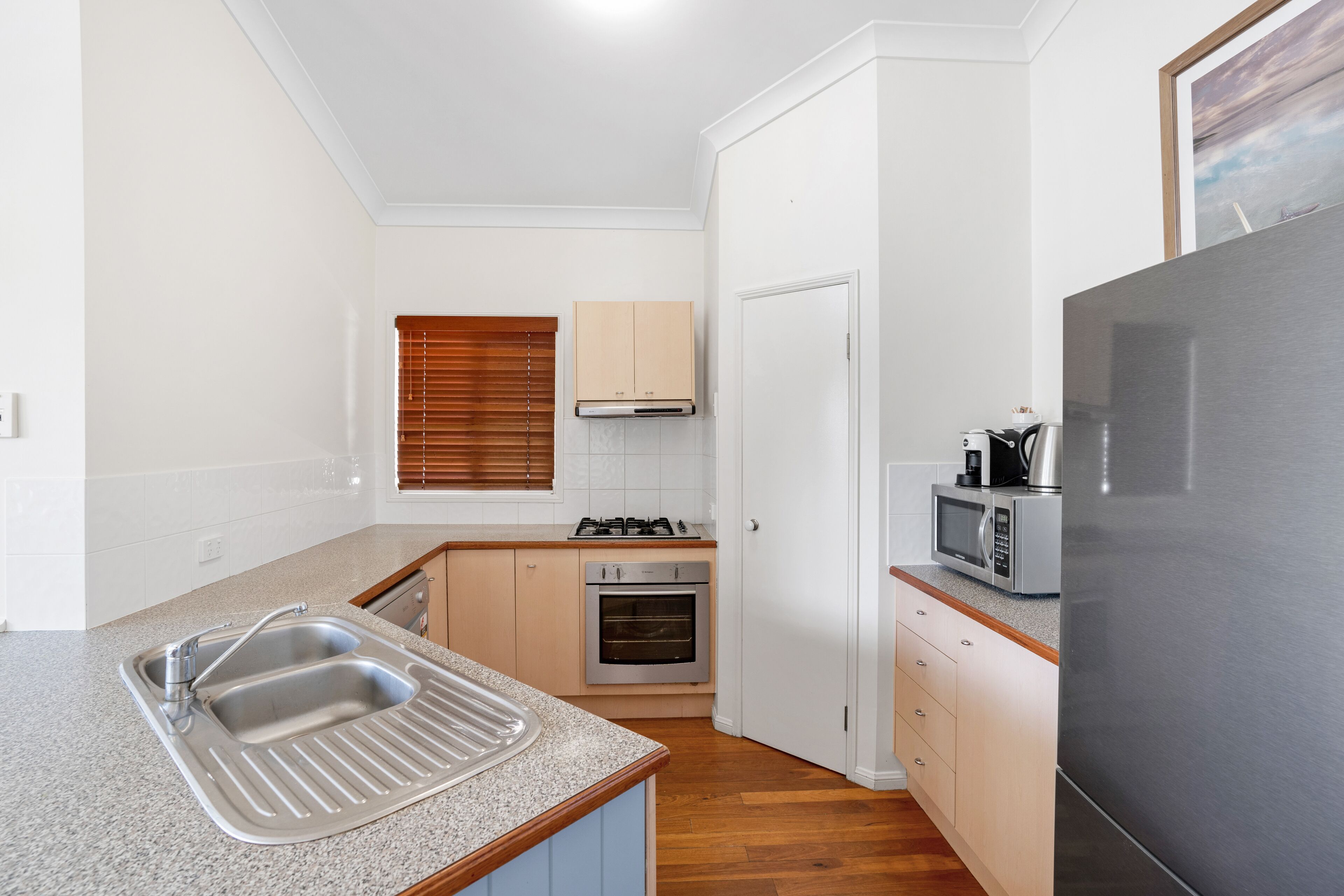 A compact kitchen with a sink, stove, oven, microwave, and refrigerator.