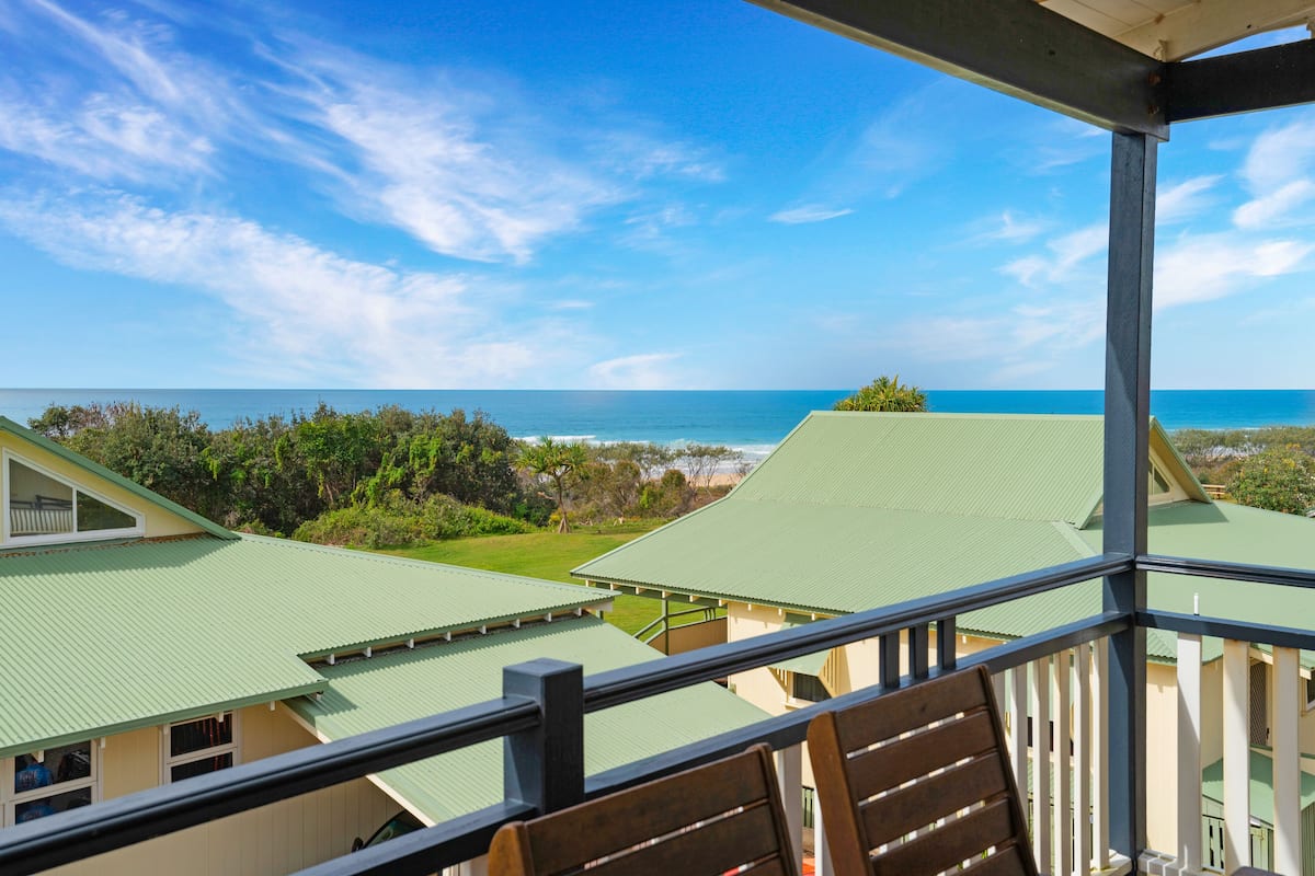 A view from a balcony overlooking a beach with a clear sky.