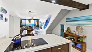 Een moderne keuken met een ingebouwde kookplaat, houten kastjes en uitzicht op de eethoek.