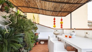 A covered outdoor dining area with white furniture, potted plants, and a bamboo ceiling. - Matteotti Apartment in Firenze (Florence)