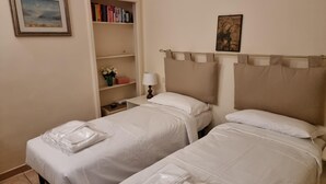 Une chambre d’hôtel avec deux lits, une bibliothèque remplie de livres, un tableau et une vue sur le ciel nocturne.