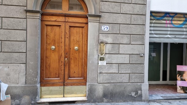 Une porte à deux battants en bois, dotée de poignées en laiton, d’une plaque de numéro et d’un petit panneau indiquant que l’accès au public est interdit.