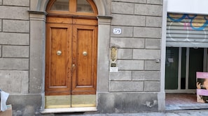 A wooden double door with brass handles, a number plaque, and a small sign indicating no public access.