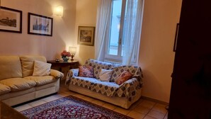 Un salon avec deux canapés, un tapis à motifs et des tableaux encadrés accrochés au mur.