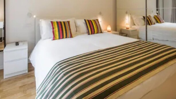 A modern hotel room with a large bed, a bedside table, a nightstand, and a mirror. - CDT Duomo in Firenze (Florence)