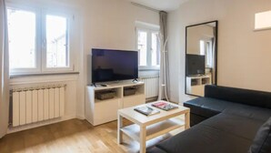 A modern living room with a flat-screen TV, a sofa, a coffee table, and a large mirror. - CDT Duomo in Firenze (Florence)