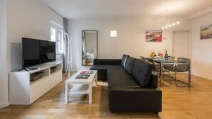 A modern living room with a black sofa, a white coffee table, and a flat-screen TV. - CDT Duomo in Firenze (Florence)