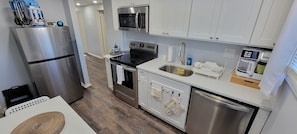 A modern kitchen with stainless steel appliances, a microwave, a sink, and a dishwasher. - Cheerful 2-Bedroom Apartment with Smart Home Tech. (Uniondale)