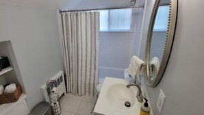 Ein Badezimmer mit weißem Waschbecken, einem Spiegel, einem Handtuchhalter und einer Duschvorhang.