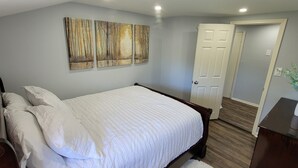 Ein Schlafzimmer mit einem Bett, einem Nachttisch, einer Tür und einem Wandbild.