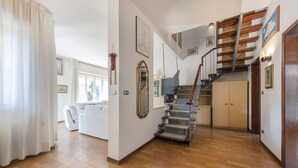 Amplia sala de estar con escalera, un piano y un sofá.