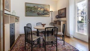 Un comedor con una mesa redonda, seis sillas, un tapete estampado y obras de arte en las paredes.