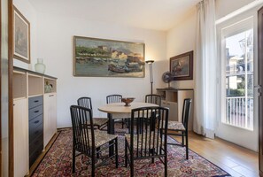 A dining area with a round table, six chairs, a patterned rug, and artwork on the walls.