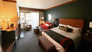 A hotel room with a bed, a sofa, a chair, a small table, and a desk with a lamp. - Spruce Peak, Studio -Ski in -Ski out (Stowe)