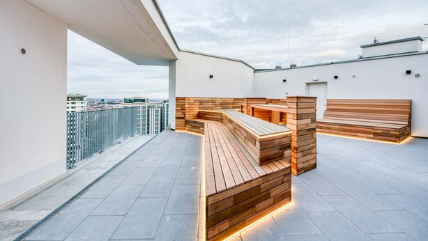 Eine Dachterrasse mit Holzbanken und Blick auf die Stadt.
