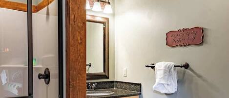 A bathroom with a glass shower door, wooden vanity, a toilet, and a towel rack.