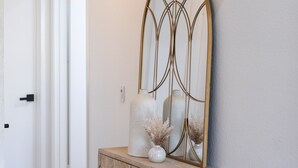 A hallway with a wooden cabinet, a mirror, and a light fixture.