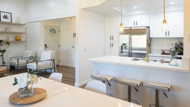 A modern kitchen with white cabinetry, stainless steel appliances, and pendant lighting.