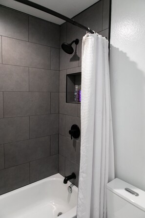 Bañera con ducha, toallas, jabón, shampoo