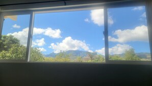 A window with a view of a mountain range and a clear blue sky. - Spacious North Shore cottage with lush mountain scenery in the country! (Waialua)